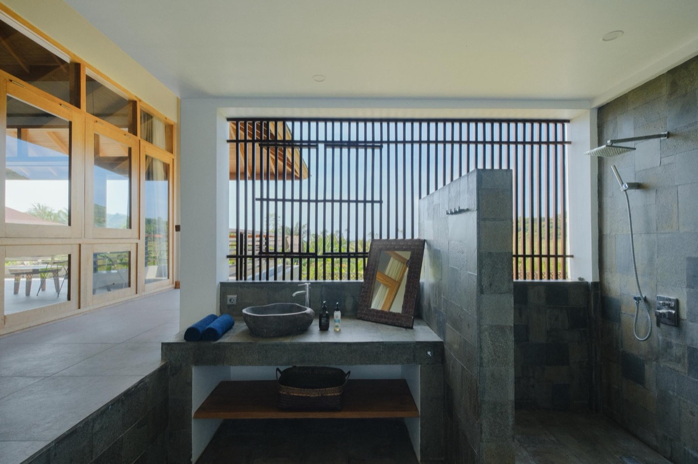 a stone bathroom with a rain shower and a slatted window over the fields