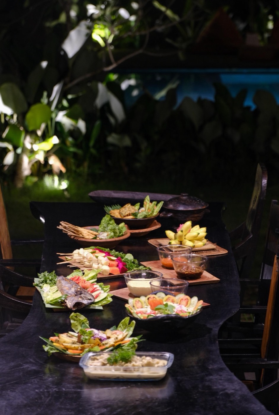 a spread of fruit and dishes on a dark table at night