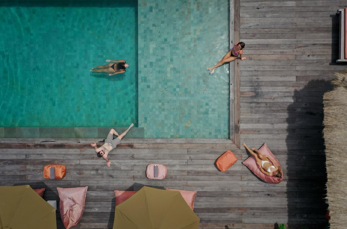 the pool from above with people swimming and beanbags on the deck