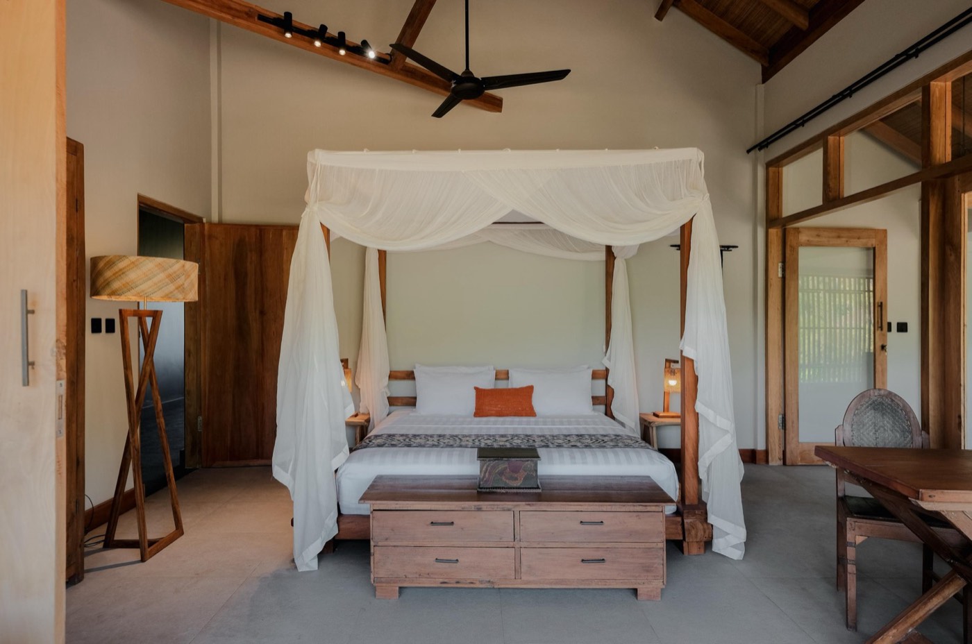 a bedroom with a canopy bed, a fan and a bench