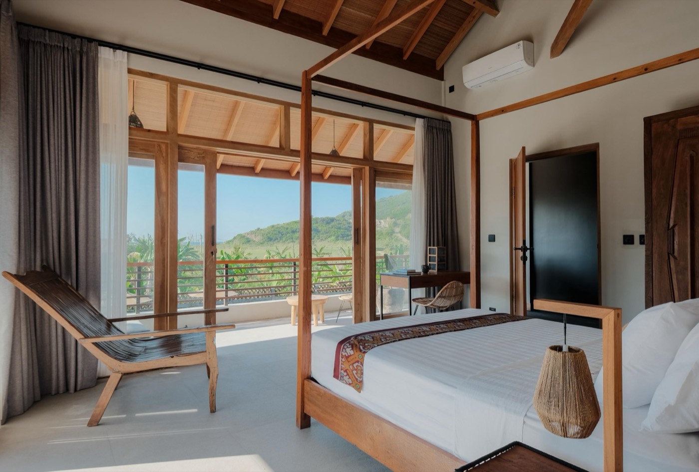 a bedroom with a four poster bed and a private terrace over the hills