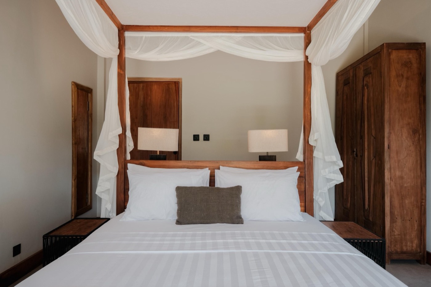 a bedroom with a canopy bed and wooden wardrobe